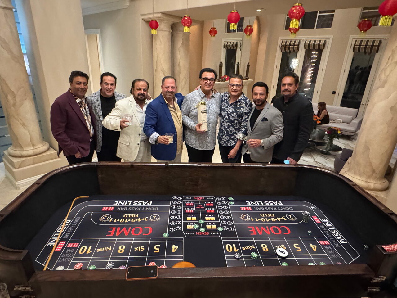 Friends celebrating around a craps table at a Bay Area mansion casino party
