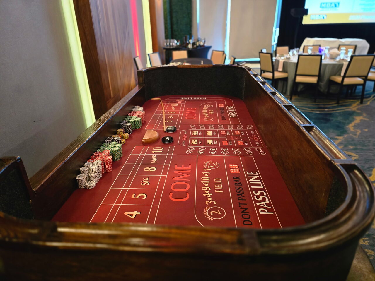 Red-felt craps table with a chip rail at a Bay Area corporate casino night