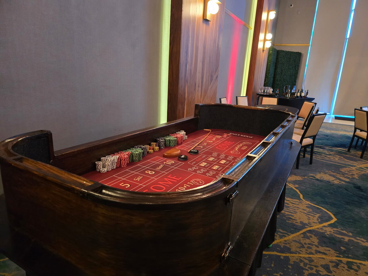 Red-felt craps table in a modern neon-lit San Francisco event space